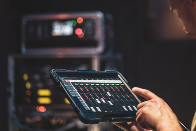 A technician adjusting equipment settings on a tablet held in front of a control panel